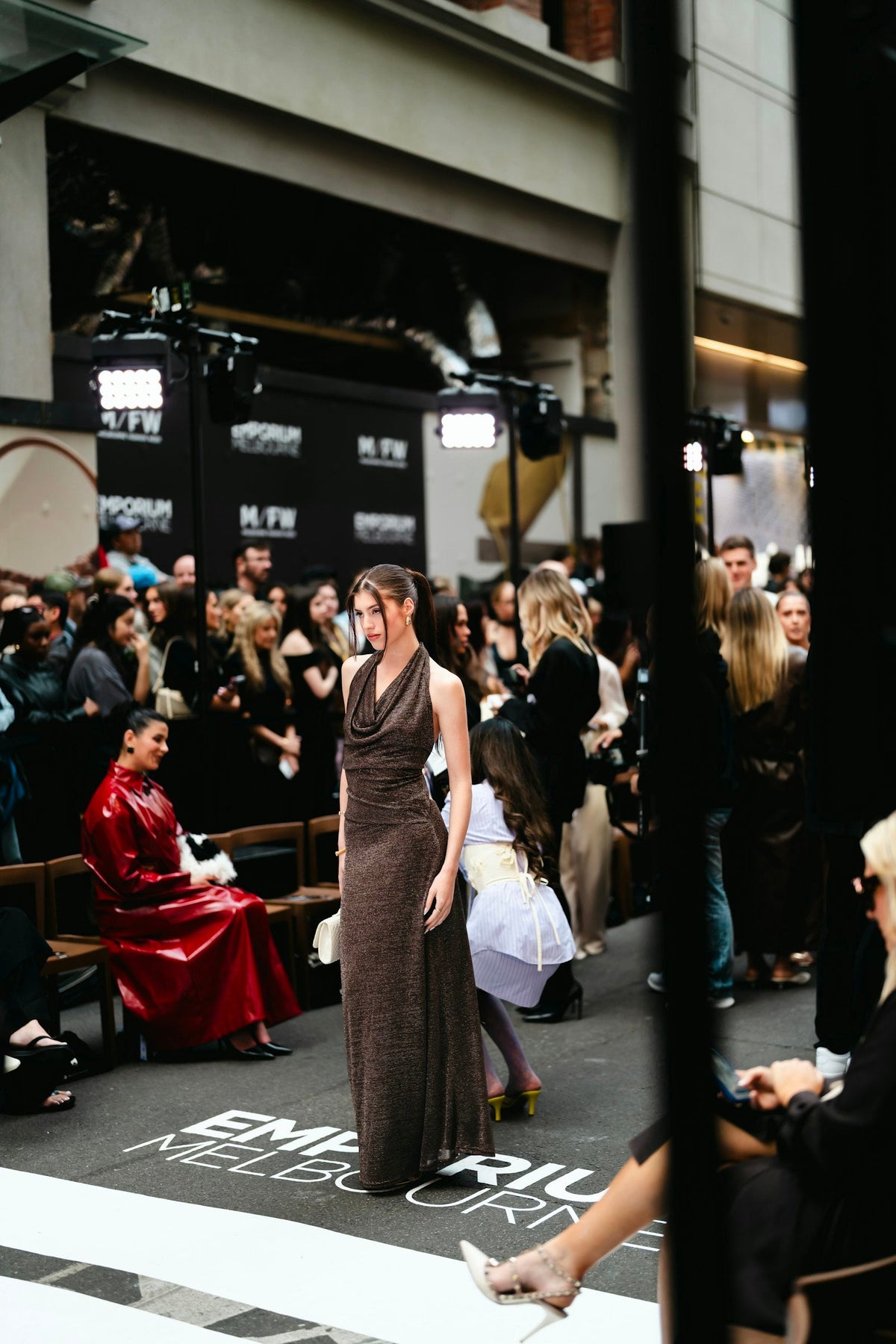 Model walks the runway at a fashion week show with the front row watching